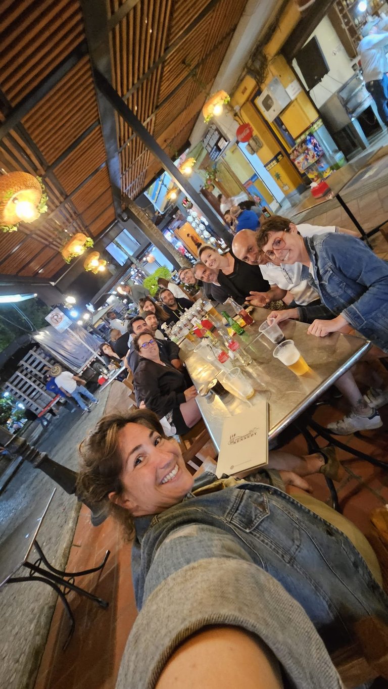 Group of people smiling at a bar counter in a rustic venue with wooden ceiling and warm lighting